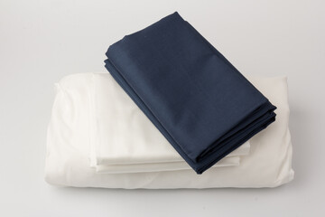 Stack of clean white and blue bed sheets on white  background, closeup.