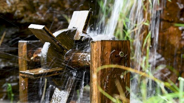Wasser plätschert auf ein kleines Holzwasserrad - Gartendekoration, Wasserlauf im Garten