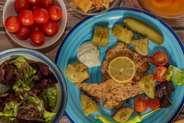 Vegetable fruit yoghurt apricot courgette chicken on blue plate and wooden table