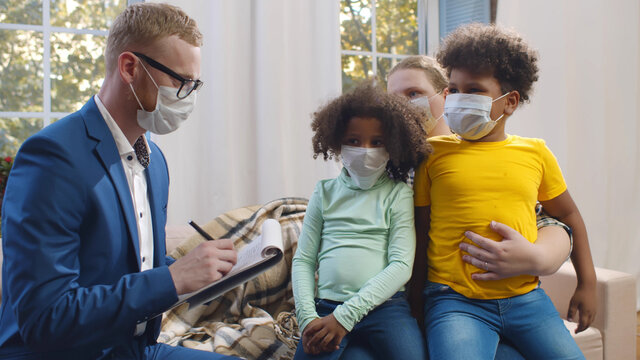 Young Social Worker In Safety Mask Visiting Foster Mother With Two Adopted Children