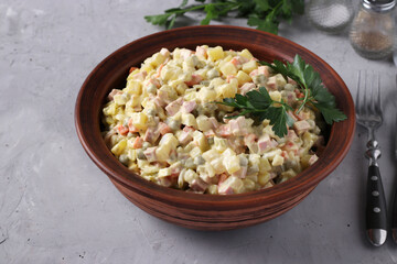 Traditional Russian salad Olivier in bowl on grey background, horizontal format.
