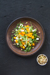 Delicious healthy pumpkin salad with arugula and cheese. Creative atmospheric decoration