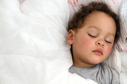 baby sleeping wrapped up in blanket after having a good sleep in bed stock photo