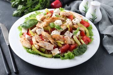 Salad with bulgur, baked chicken, bell pepper, basil and feta on a white plate, Closeup. Horizontal format