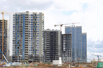 Construction of modern multi-storey buildings. New development of a residential area. House frames, construction cranes and building materials at the construction site.