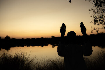Fototapeta na wymiar Silhouette Young asian muslim man praying on sunset,Ramadan festival concept
