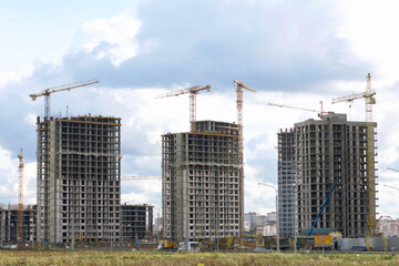 Construction of modern multi-storey buildings. New development of a residential area. House frames, construction cranes and building materials at the construction site.