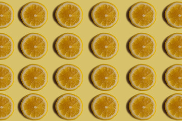 Fruit pattern. Repetition of lemon wedges on a yellow background. Colorful food background. Top view on round lemon wedges arranged in a row. Healthy food and agriculture concept.
