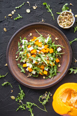 Delicious healthy pumpkin salad with arugula and cheese. Creative atmospheric decoration