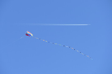 Gegenverkehr mit Drachen und Flugezug vor blauem Himmel