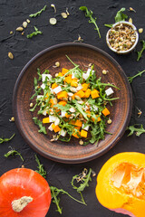 Delicious healthy pumpkin salad with arugula and cheese. Creative atmospheric decoration