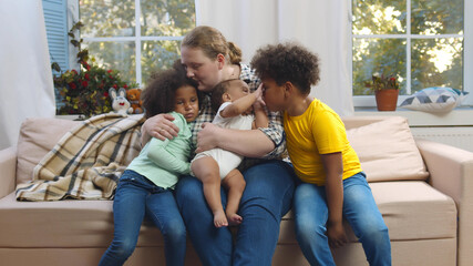 Portrait of caucasian mother with mixed race children sitting on couch in living room