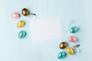 Easter greeting card with colorful easter eggs on blue background. Top view, flat lay with space for your text.