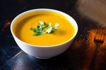 Yellow cream soup on the restaurants table, pumpkin and carrot