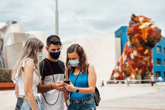 Group Of Friends With Surgical Masks Searching On A Smartphone