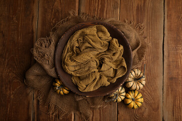 Prop digital background of newborn photography. wooden basket  with yellow blanket and decorated with small pumpkins on old wooden background.