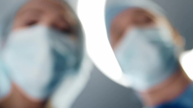 First-person view of the oxygen mask in doctor's hand. Patient looking to the face of the surgeons in protective masks. Anesthesia and narcosis.