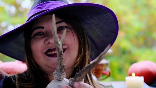 witch in a black copack makes magic passes over a skull with horns of a sacrificial animal, the concept of the Halloween holiday, love spell, clairvoyance, preparation for a party