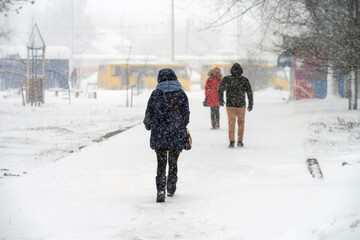 Pedestrians make their way through the blizzard in the city. Selective focus.