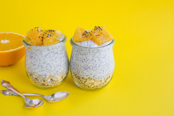 Pudding with chia, oat flakes and orange in the glass jars on the yellow  background