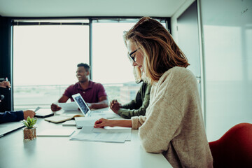 Business woman smiling while reading through letter from boss outlining goals to be reached for the company 