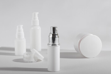 Fototapeta na wymiar Set of white cosmetic bottles and jars with hard shadows. Home and beauty salon care concept