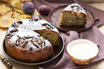 Plum pie with nuts and chocolate on a wooden background. Rustic style.