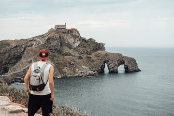 Young man with a hat in front of the Gaztelugatxe Island