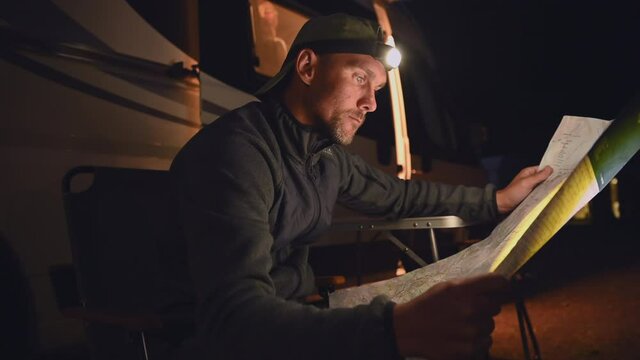 Caucasian Men in His 30s Browsing Paper Map of Local Area in Front of Class B Motorhome RV Camper Van