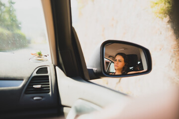 Naklejka premium View of a young woman on the rearview mirror of a car