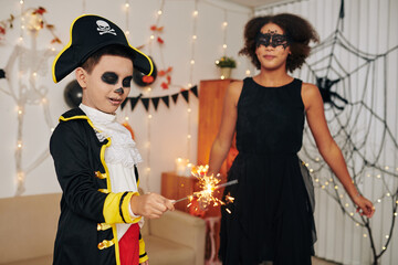 Exited boy in pirate costume burning Bengal light at Halloween party