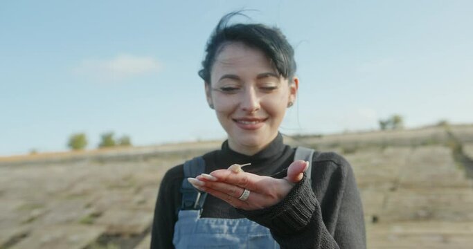 Happy woman demonstrating snail on hand while working on farm on sunny summer day