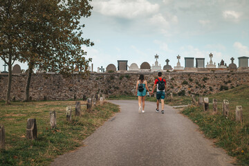 Fototapeta na wymiar Couple walking by a path near a cemetery in Europe