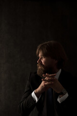 dark portrait of a business man, sitting and pensively looking out the window, in front of the hand, filming in a dark key