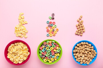 Various corn flakes in bowls on pink background