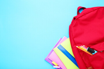 Backpack with school supplies on blue background