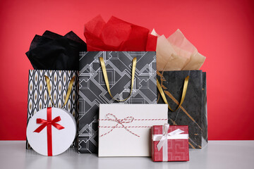 Shopping paper bags and gift boxes on red background