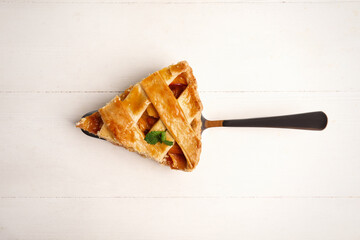 Slice of delicious fresh peach pie on white wooden table, top view