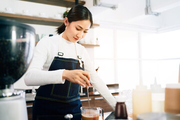 A female barista student attentively measured and added milk in the coffee while the teacher...