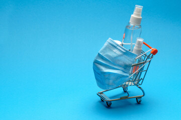 protective masks and antibacterial disinfection sanitizer gel in a small shopping trolley cart on...