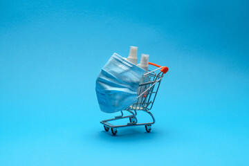 protective masks and antibacterial disinfection sanitizer gel in a small shopping trolley cart on...