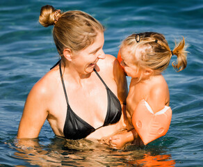 Mother playing with daughter in sea