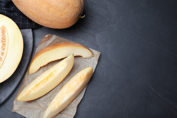Slices of delicious honey melon on black table, flat lay. Space for text