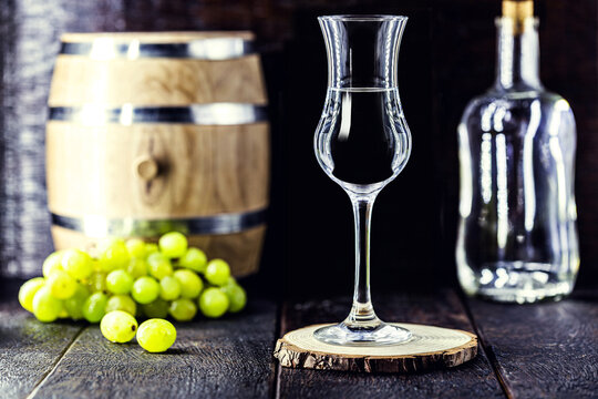 Glass of brandy based on grapes, called bagaceira in Portugal and in Italy Grappa or Graspa, with oak barrel in the background