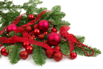 red Christmas tree ornaments on a green pine Christmas tree branch isolated on white
