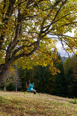 Girl on a swing in the autumn mountains