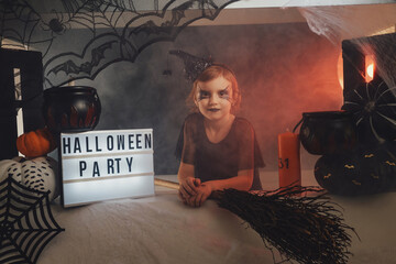 Smokey and atmospheric halloween party's stand and little girl in dark custom clothing which cosplaying witch.