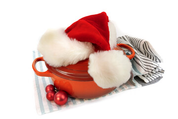 Obraz na płótnie Canvas Santa Claus red Christmas hat on a red cast iron baking dish isolated on white
