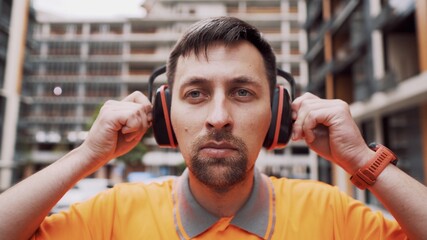 Man wearing safety equipment hearing protection. Worker wearing noise cancelling ear defenders or...