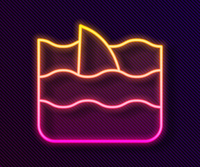 Glowing neon line Shark fin in ocean wave icon isolated on black background. Vector.
